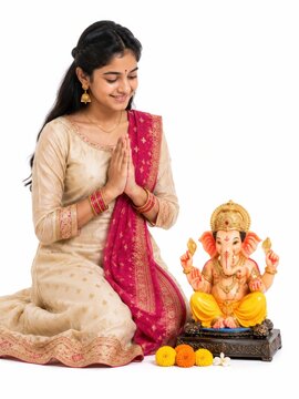 young indian woman sitting with lord ganesha sculpture and doing praying gesture