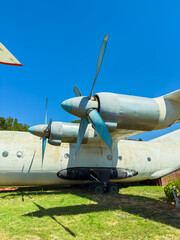 Old plane with propellers resting on the ground under a clear sky, located in a historic aircraft display area near a park in a sunny afternoon © DSMT