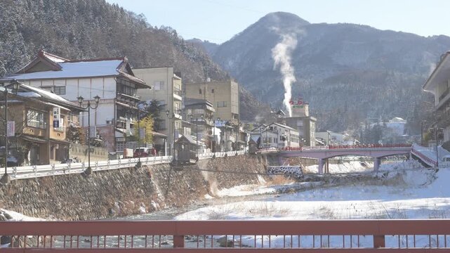 湯けむりが立ち上る雪景色の渋温泉街と横湯川の全景
