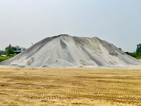 Large stockpile of fine crushed stone aggregate at a quarry and construction materials distribution site.