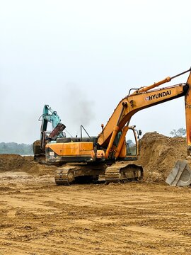 Sarawak, Malaysia - 24 September 2026: Two hydraulic excavators parked side by side on a sandy ground surface at an active construction project.