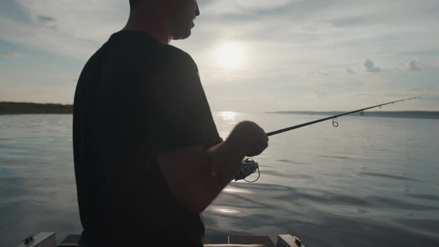 Angler stands in the boat and fishing on the lake