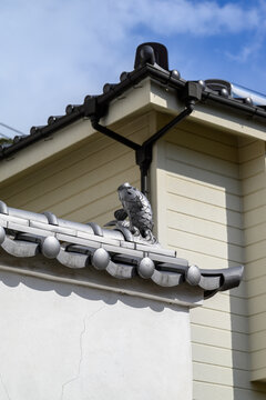 Scenic landscape view of a carp ornament adorning traditional Japanese roof tiles and a white wall under a blue sky in Japan