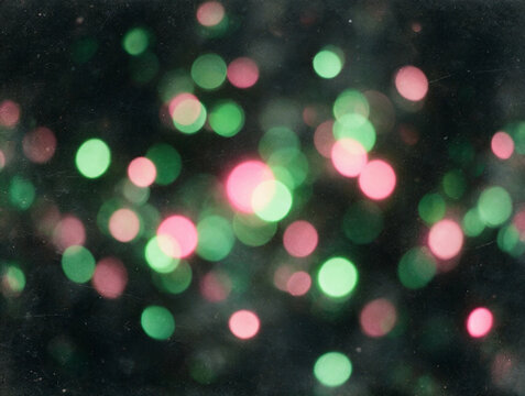 Efecto desenfocado de luces bokeh en tonos verdes y rosas sobre una superficie oscura, ideal para composiciones festivas, conceptos navide&ntilde;os, dise&ntilde;o gr&aacute;fico y texturas de iluminaci&oacute;n.