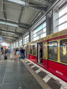 Berlin Ostkreuz station platform busy with passengers boarding and alighting a red and yellow S-Bahn train, showcasing urban public transport infrastructure and daily city commuting in Germany