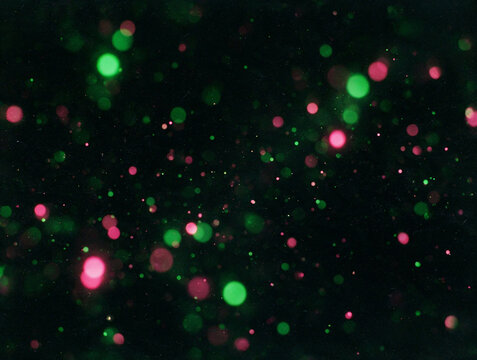 Part&iacute;culas resplandecientes y peque&ntilde;os puntos de luz bokeh verdes y rosados dispersos sobre un entorno oscuro, perfecto para efectos m&aacute;gicos, composiciones nocturnas y arte digital. Destellos fiesta