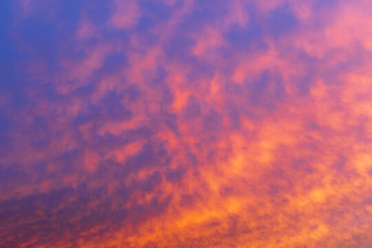 Beautiful wide view of colorful sunset sky with fiery orange and purple clouds