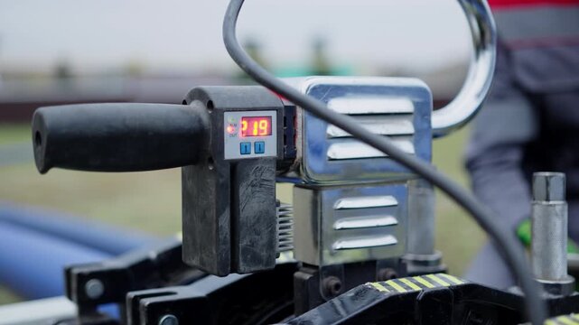 Innovative butt welding machine with small digital screen and handle connects pipes outdoors closeup. Plastic pipeline maintenance technology