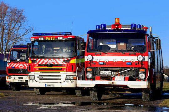 Three fire trucks parked in a yard, blue sky background. 