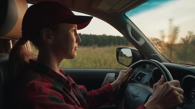 Young woman in red shirt steers 4x4 off road car in the wild on sunset