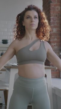 Young woman in sportswear working out doing sports indoors in kitchen in apartment. Active lifestyle and healthy people concept.
