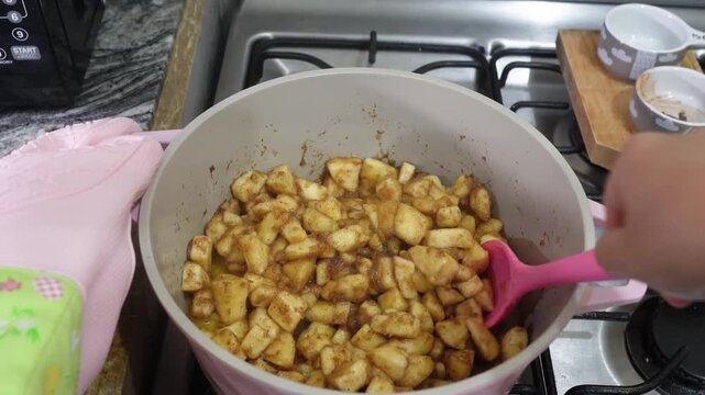 Female Hands Mixing Ingredients in a Pot to Make Apple Jam