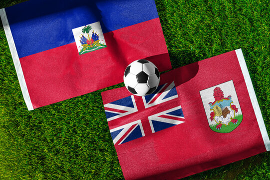 Haiti vs. Bermuda football match. National flags on green grass with soccer ball in the middle. Football background for international match.