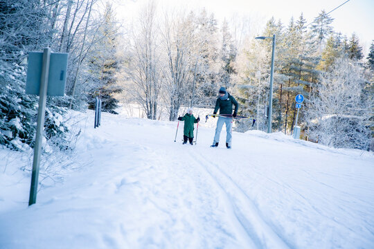 A father helps his toddler learn cross-country skiing on a snowy trail in Helsinki region, Finland, during an active winter family outing.