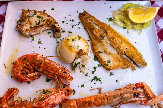 Close-up view of gourmet mixed grilled seafood platter with grilled fish fillet, cuttlefish, swordfish steak, large prawns, langoustine scampi, typical Mediterranean Italian food.