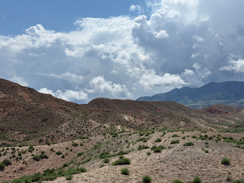 Expansive desert landscape with rolling hills under a dramatic sky filled and distant mountain