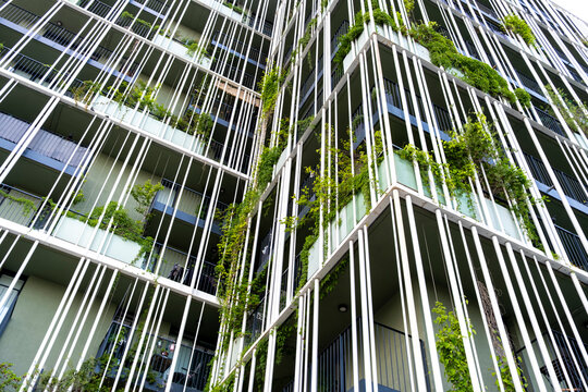 Contemporary architecture with vertical metal fins and greenery, combining terraces, geometric facade design and urban vegetation.
