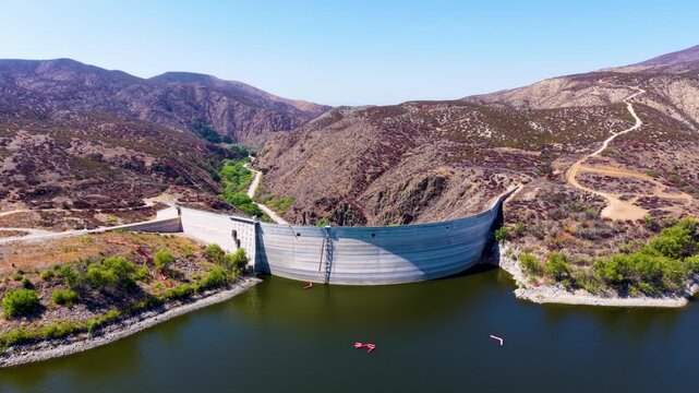 Aerial perspective of a Dam at Lake Vail California. A slow withdrawal from up close to a higher altitude reveals the mountainous terrain surrounding this lake in the Mountains of California
