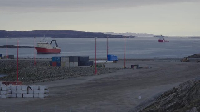 Telephoto shot of vessel Mersey Venture navigating port channel while icebreaker Molly Kool sits anchored in background off Baffin Island