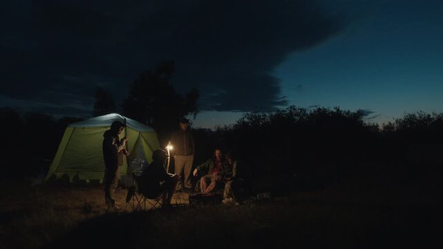 Group of men camping in the wild and gather near the bonfire and talk with each other. Fishermen camping and talk stories at night