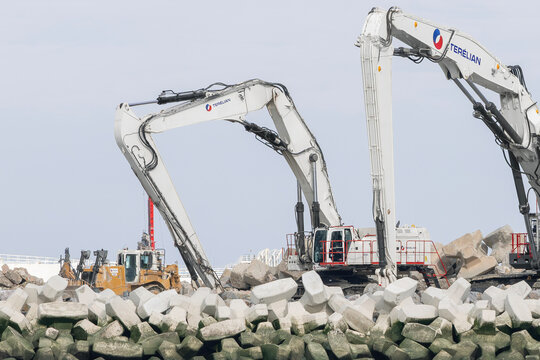 Le Havre, France - August 26th 2026 : View on a white long reach crawler excavator CAT 395 for earthworks to construct a new offshore breakwater.