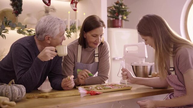 Caucasian family decorating gingerbread cookies in kitchen at home site