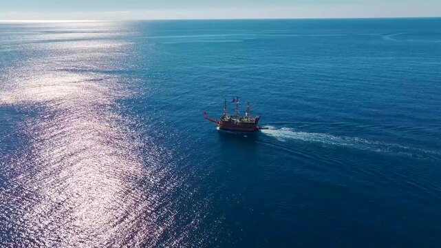 Aerial Video Classic Pirate Ship Sailing Across The Azure Sea, Heading Toward An Old Coastal Port Under A Sunny Sky