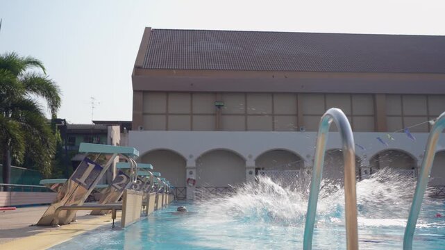 Caucasian young boy diving to outdoor swimming pool from starting block.