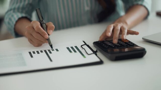 Female office worker sitting on desk managing financial files and reviewing reports