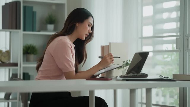 Asian female sitting at a desk using laptop working from home