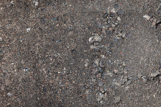 High-resolution close-up of weathered asphalt pavement showing exposed aggregate, grit, small stones and cracks. Ideal for backgrounds, texture overlays, urban design and construction visuals