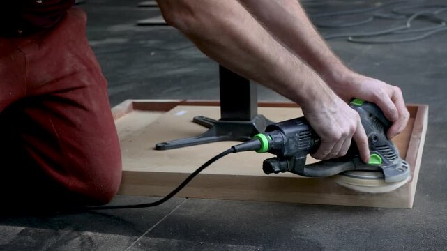 Worker Sanding Wooden Table with Orbital Sander