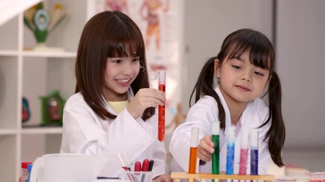 Two Young Schoolgirls Conducting Chemistry Experiments with Test Tubes in Lab