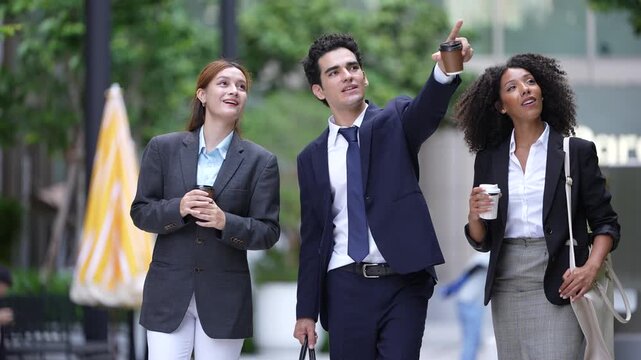 Team walks past a yellow cafe umbrella into a close two-shot, the conversation carrying on from the plaza to the camera, a long take for commute and culture edits