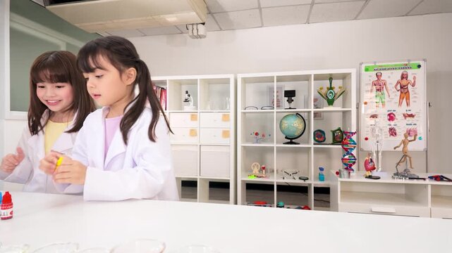 Two Young Schoolgirls in White Lab Coats Conducting Science Experiment