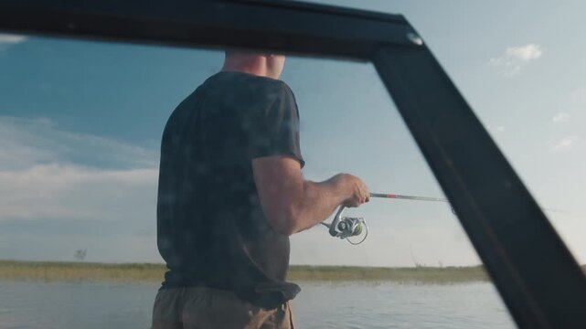 Amateur angler fishing on the river from a boat at sunset