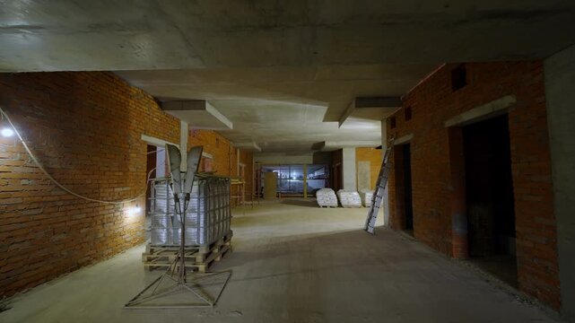 Underground corridor features stacked construction materials and ladder. Space highlights raw industrial environment during renovations