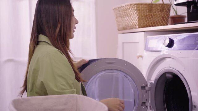 Asian woman sorting laundry clothes into washing machine at home