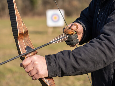 Archer preparing to shoot an arrow at a target in a field  