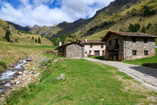 Traditional stone houses and a clear mountain stream in the scenic alpine village of Case di Viso near Ponte di Legno, Lombardy, Italy.