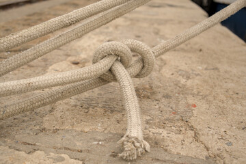 Close-up of a sheet bend knot tied in braided rope on a concrete pier in Rijeka harbor, Croatia. Marine knot detail. © YuliiaKettu