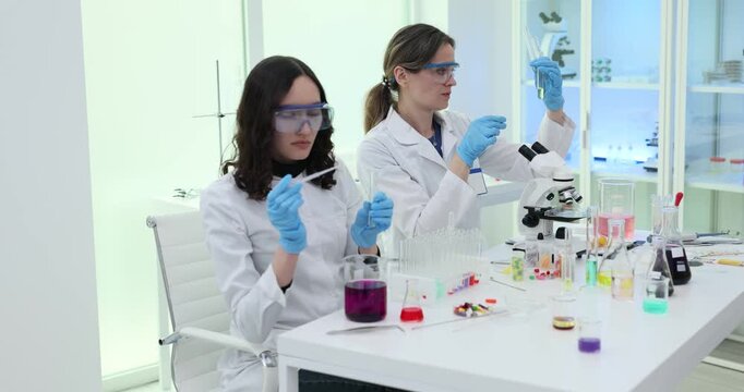 Lady scientist uses pipette to transfer violet solution into transparent test tube. Women prepare unusual chemical sample for scientific examination