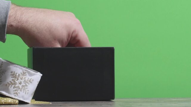 Removing gift wrapping ribbons from the box on green screen before the holiday season
