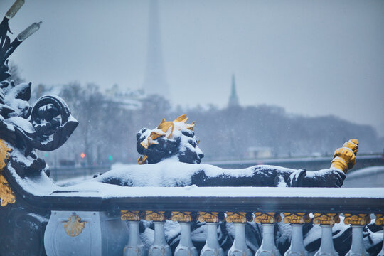 Close-up of an ornate snow-covered sculpture on the Pont Alexandre III bridge in Pari