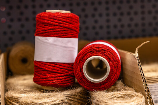 Red and brown spool of natural jute twine displayed on a store shelf, with the rustic fiber cord partially unwound