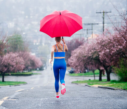 White woman running with a red umbrella on rainy street