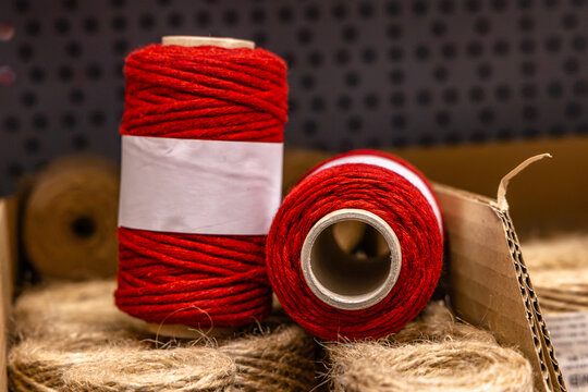 Red and brown spool of natural jute twine displayed on a store shelf, with the rustic fiber cord partially unwound