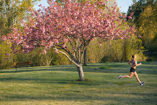 White runner jogging past blossoming cherry tree