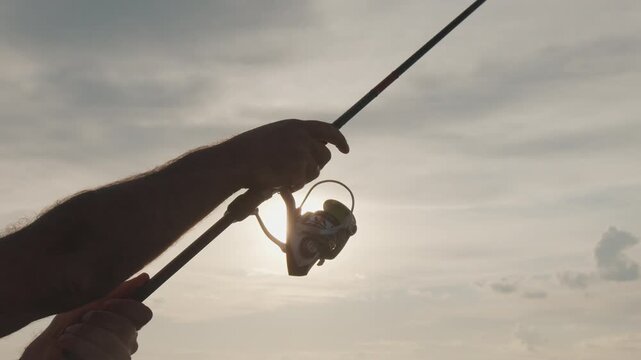 Amateur angler fishing on the river from a boat at sunset