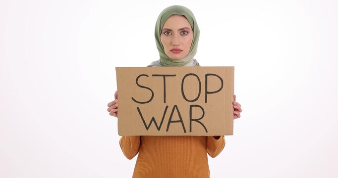 Serious Muslim woman holds cardboard sign with words Stop War. Female shows strong desire for peace safety and human dignity against white background